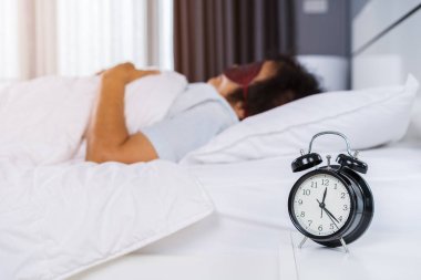 Göz maskeli yaşlı kadın yatak odasında bir yatakta uyuyor.