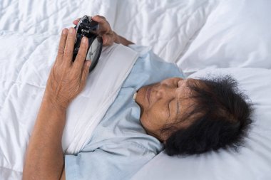 Yatakta son sınıf öğrencisi sabah alarmındaki erteleme düğmesine basıyor. 