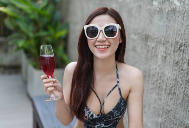 sandalye ve yüzme havuzunda bir cam tutan kadın