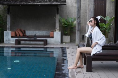 Genç kadın kendini yüzme havuzunda bir havlu ile silinerek