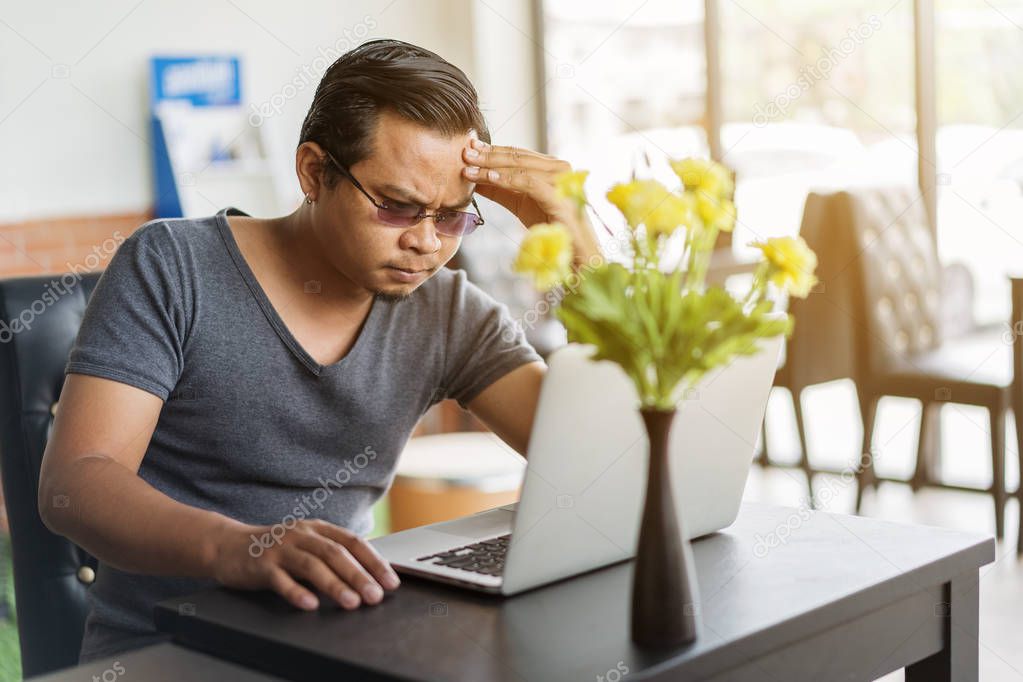 man under a lot of stress using laptop computer in cafe