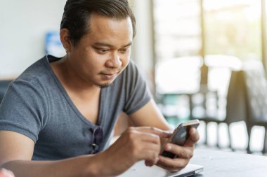 Genç adam bir kafede akıllı telefon kullanıyor.