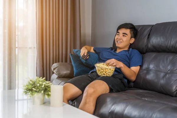 Νεαρός Άνδρας Τρώει Ποπ Κορν Ενώ Κάθεται Έναν Καναπέ Στο — Φωτογραφία Αρχείου