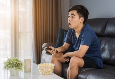 Genç adam TV izlerken şok oldu ve oturma odasında kanepede oturdu.