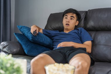 Genç adam TV izlerken şok oldu ve oturma odasında kanepede oturdu.