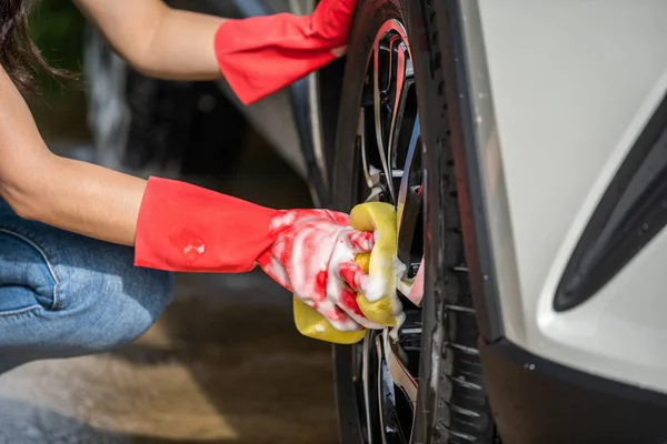 彼女の車のホイールを洗う女性持株スポンジ — ストック写真