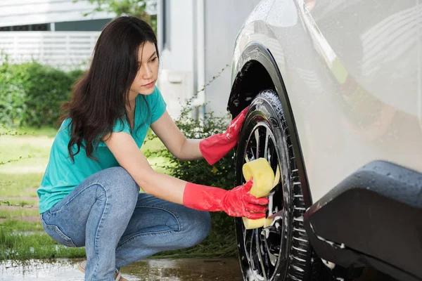 彼女の車のホイールを洗う女性持株スポンジ — ストック写真