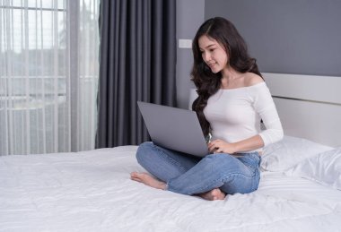 yatakta bir dizüstü bilgisayar kullanan kadın