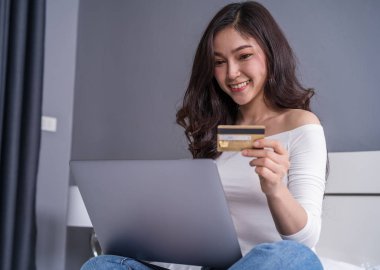 alışveriş online kredi kartı ve dizüstü bilgisayar bir yatakta kadın