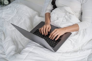 closed-up woman using a laptop computer on bed clipart