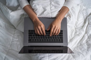 kapalı-up kadın yatakta bir dizüstü bilgisayar kullanarak
