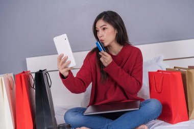 mutlu kadın tablet bir yatakta kredi kartı ile online alışveriş için kullanma