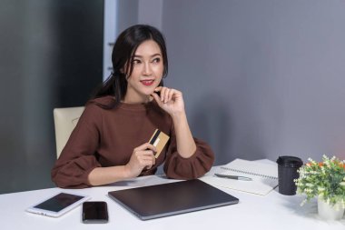 düşünme ve kredi kartı dizüstü bilgisayar ile masaya tutan kadın