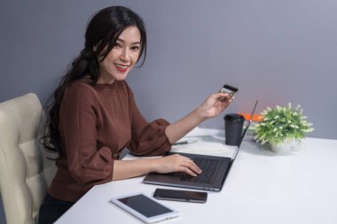 online kredi kartı ile alışveriş için dizüstü bilgisayar kullanan mutlu kadın