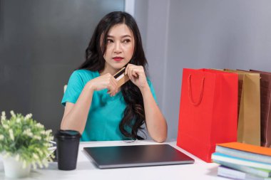 düşünme ve kredi kartı dizüstü bilgisayar ile masaya tutan kadın