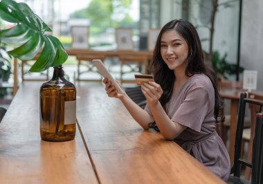 kafede tablet ile online alışveriş için kredi kartı kullanan mutlu kadın