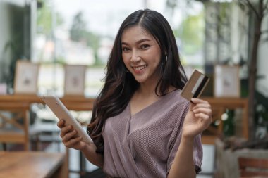 kafede tablet ile online alışveriş için kredi kartı kullanan mutlu kadın