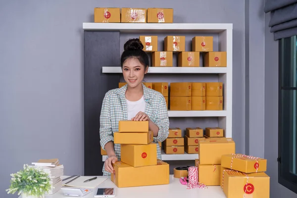 young woman entrepreneur with parcel boxes in her own job shopping online business at home