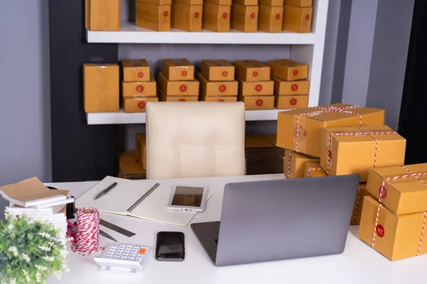 laptop computer on a table and parcel box ready for shipment to customers in home office. Startup business