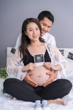 mutlu hamile kadın ve kocası ultrason tutan yatakta fotoğraf tarama