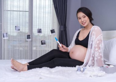 Hamilelik testi yatağa tutan hamile kadın