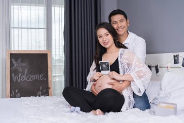 mutlu hamile kadın ve kocası ultrason tutan yatakta fotoğraf tarama