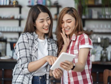 bir kafede dijital tablet kullanan iki mutlu kadın