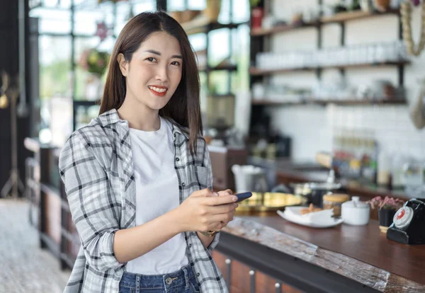 Mujer feliz usando teléfono inteligente en la cafetería — Foto de Stock