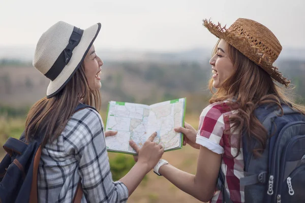 two woman searching direction on location map while traveling