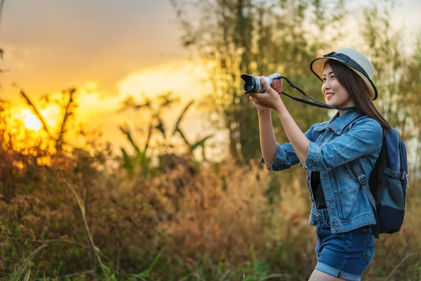 Τουριστική γυναίκα λαμβάνοντας μια φωτογραφία με τη φωτογραφική μηχανή στη φύση με ηλιοβασίλεμα — Φωτογραφία Αρχείου