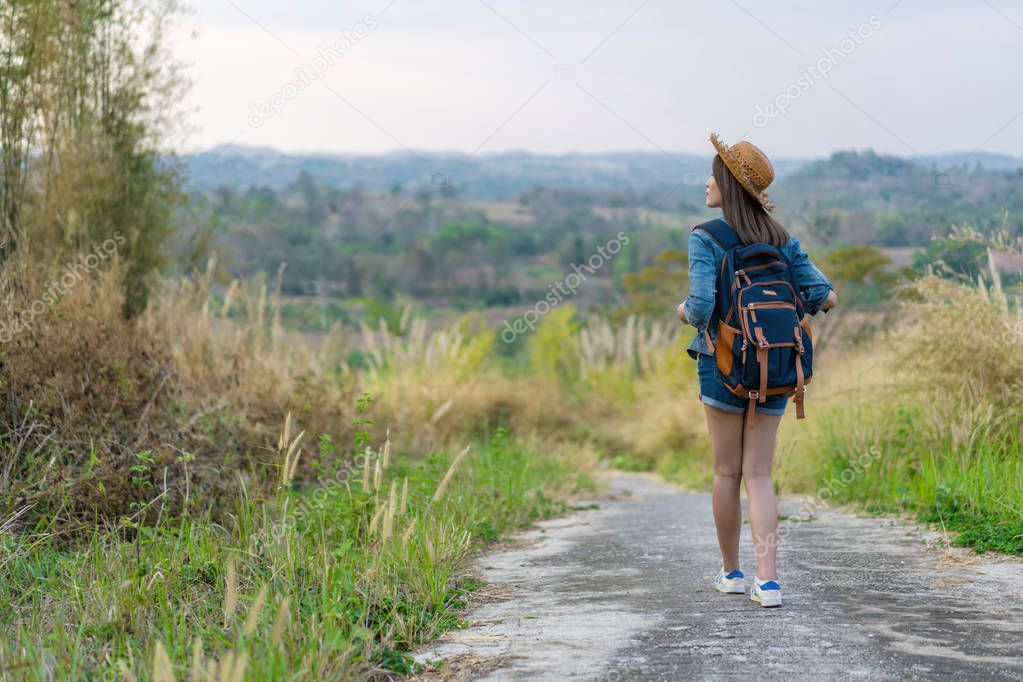 woman with backpack walking on footpath in nature