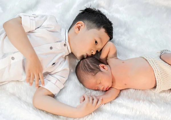 Little boy kissing his newborn baby brother on bed — Stock Photo, Image