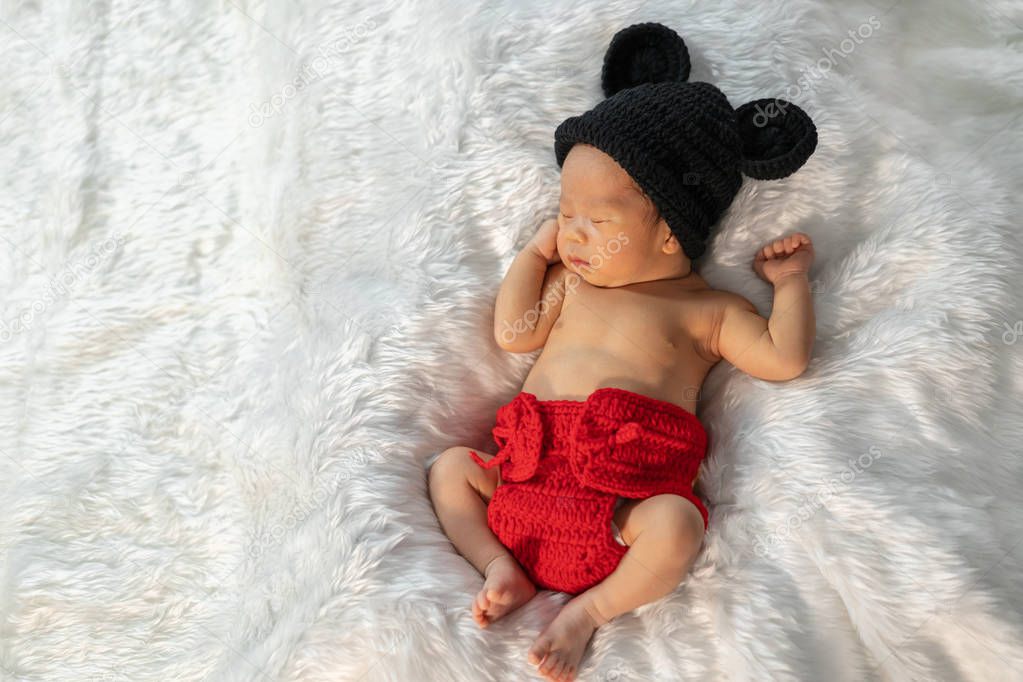 newborn baby in mouse costume sleeping on fur bed