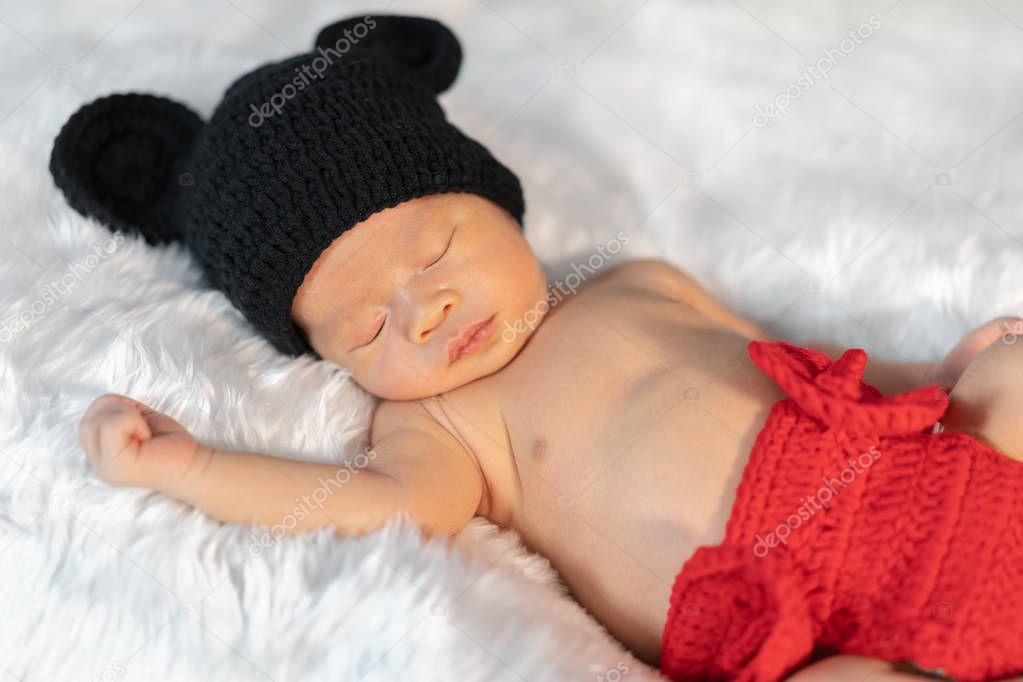 newborn baby in mouse costume sleeping on fur bed
