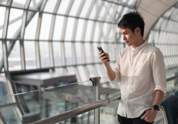 Hombre que espera el vuelo y el uso de teléfono inteligente en el aeropuerto — Foto de Stock