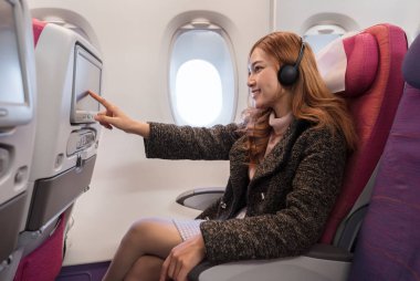 Uçuşta LCD eğlence ekranına dokunan kadın