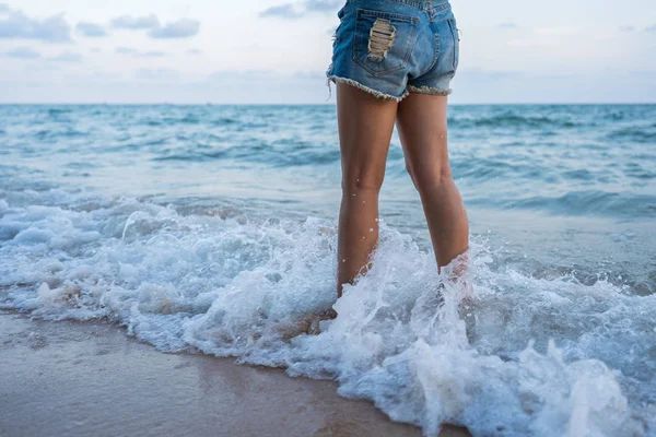 Pierna de mujer con olas de mar salpicando en la playa — Foto de Stock