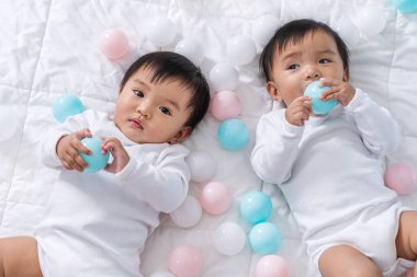 yatakta renk topu oynayan neşeli ikiz bebekler