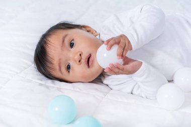 neşeli bebek yatakta renk topu oynuyor