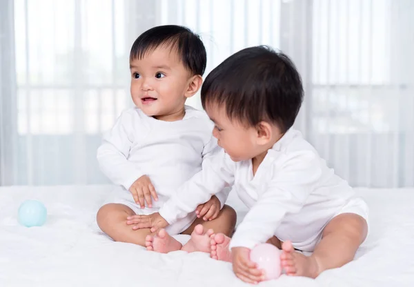 침대에서 컬러 볼을 연주하는 쾌활한 쌍둥이 아기 — 스톡 사진