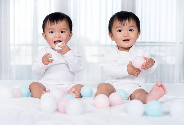 침대에서 컬러 볼을 연주하는 쾌활한 쌍둥이 아기 — 스톡 사진