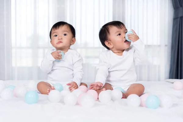 Allegri bambini gemelli che giocano a palla a colori sul letto — Foto Stock