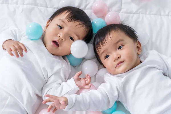 Cheerful twin babies playing color ball on bed — Stock Photo, Image