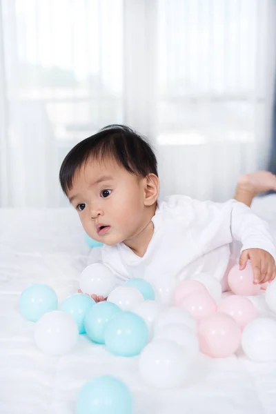 Cheerful baby playing color ball on bed — Stock Photo, Image