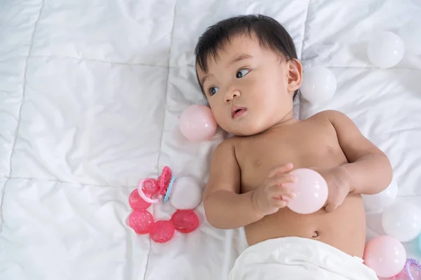 Bebê jogando bola de cor em uma cama — Fotografia de Stock