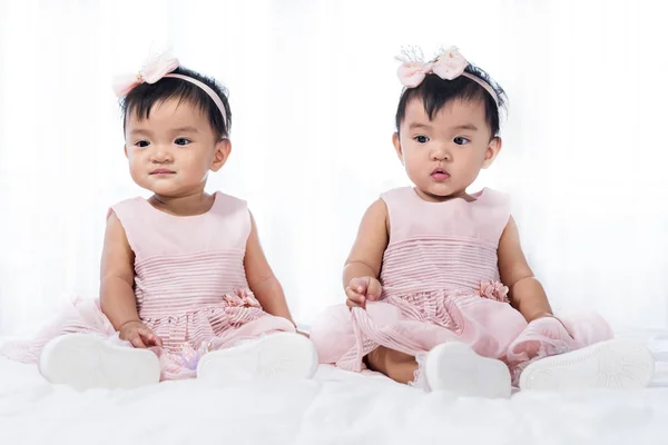 Two twin babies in pink dress on bed — Stock Photo, Image