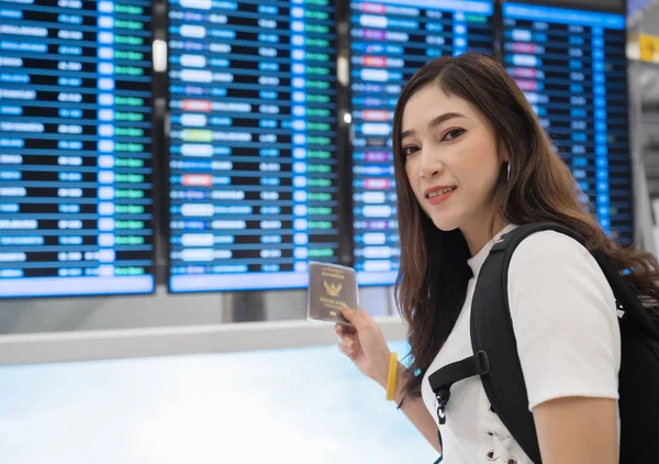 kadın, uçuş bilgi panosu ile pasaportunu tutan