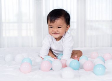 neşeli bebek yatakta renk topu oynuyor