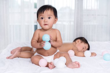 yatakta ikiz bebekler, bir oyun renk topu, bir uyku