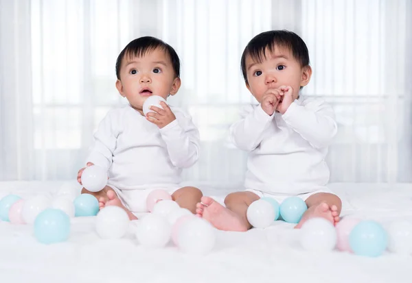 Cheerful twin babies playing color ball on  bed — Stock Photo, Image